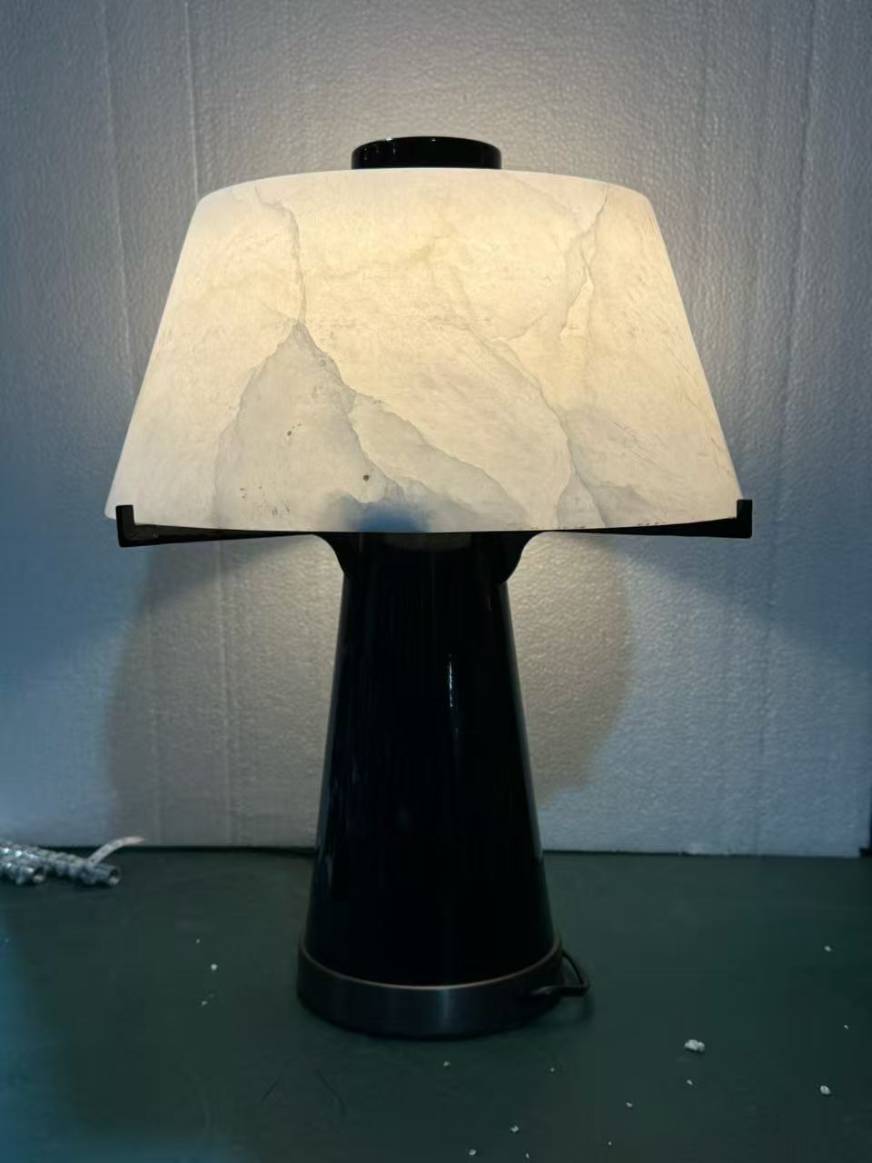 Table light with a softly illuminated shade and tapered dark base in the workshop