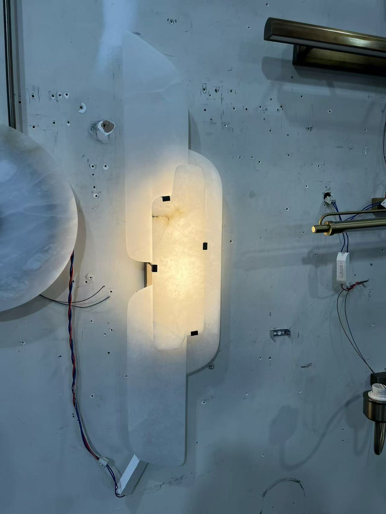 Wall light with overlapping translucent panels around a central dark metal structure in the workshop