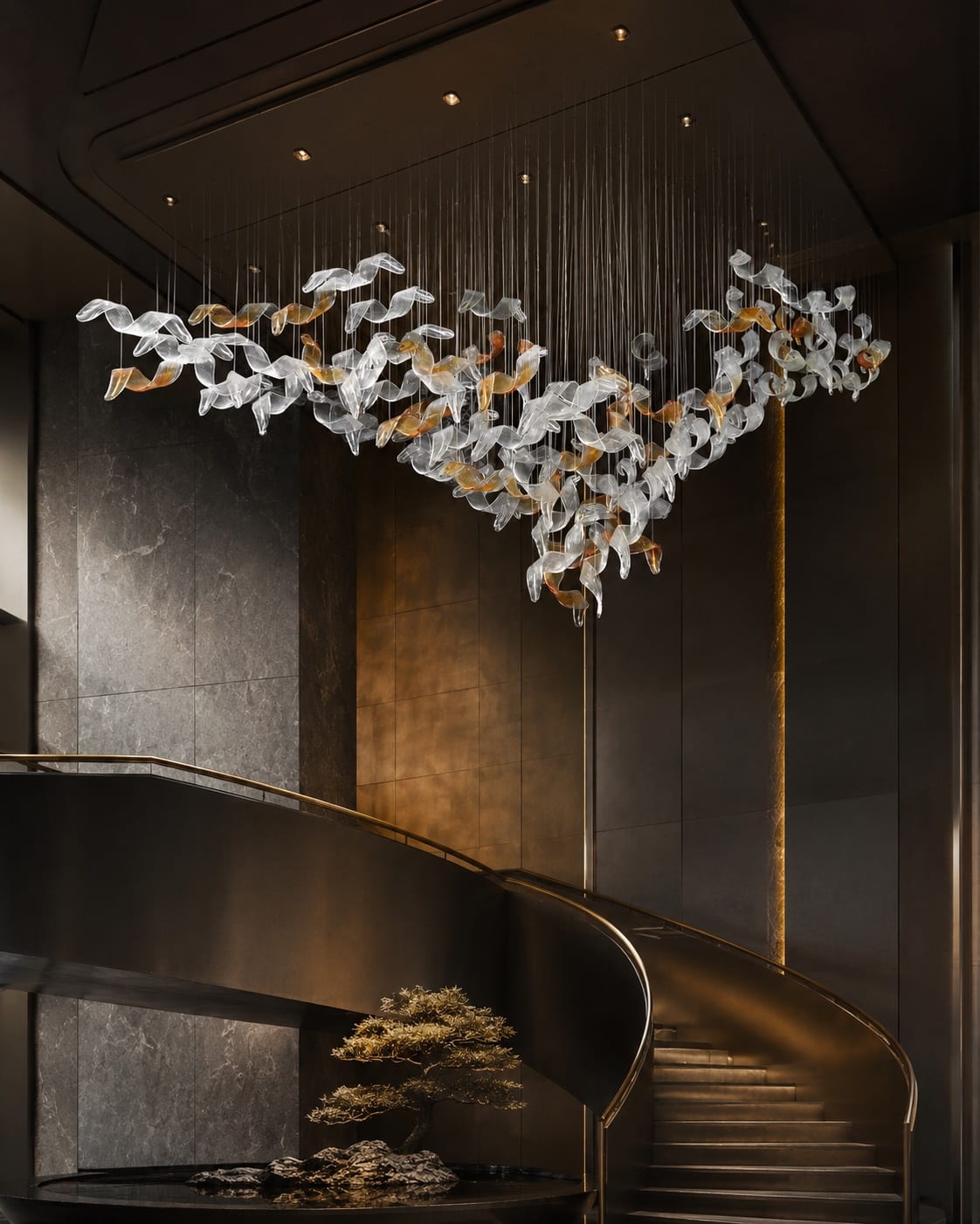 Floating glass ribbon chandelier with clear and amber elements suspended above a curved staircase.