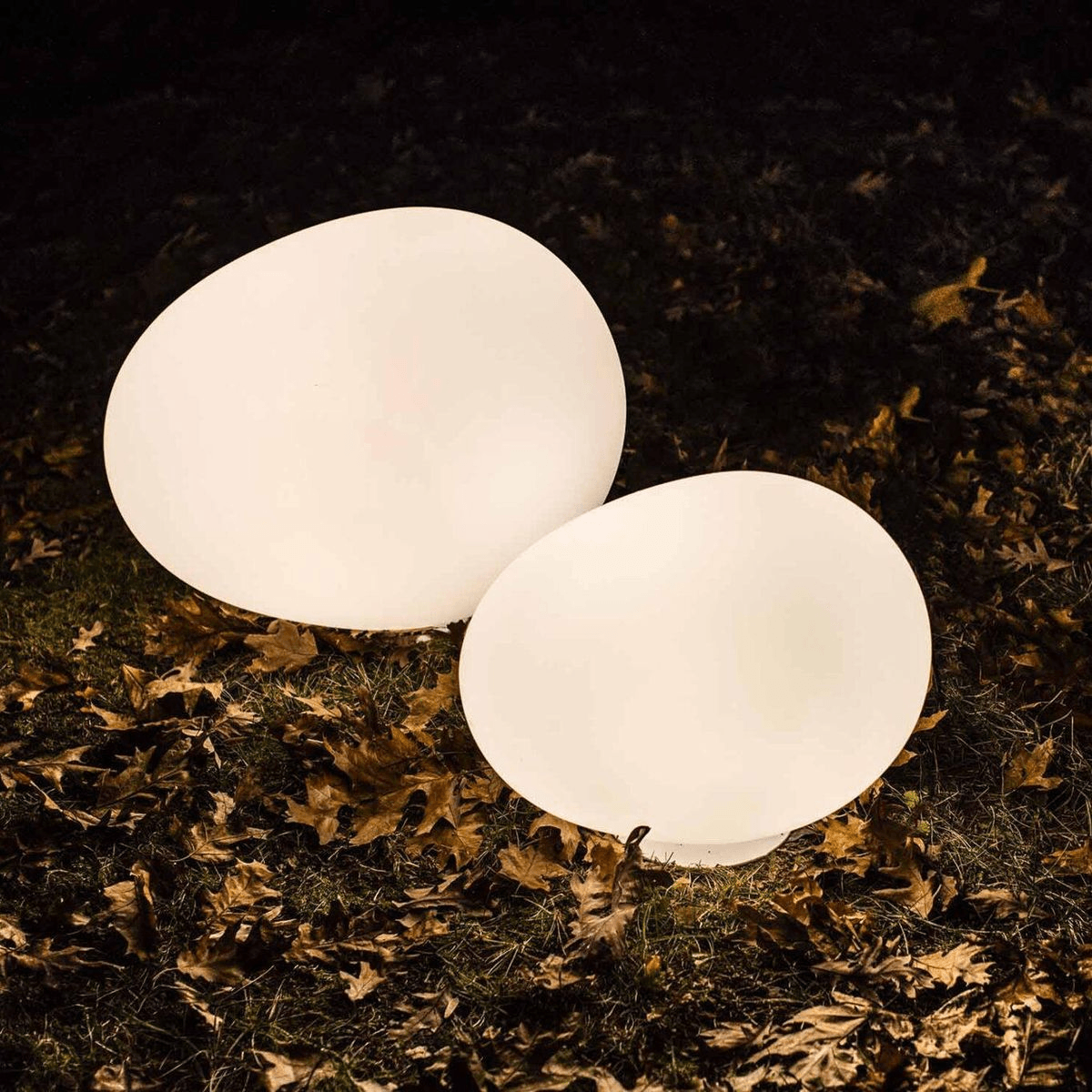 Two custom spherical illuminated landscape lights positioned in a garden at night.