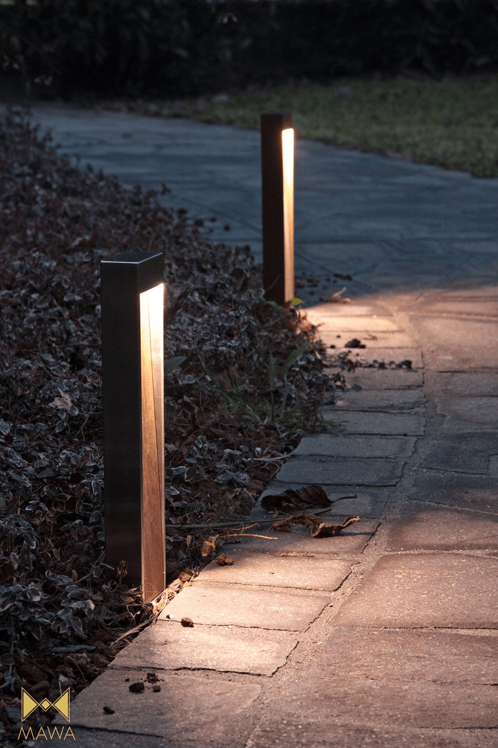 Two custom linear pathway bollards illuminating a curved landscape walkway.